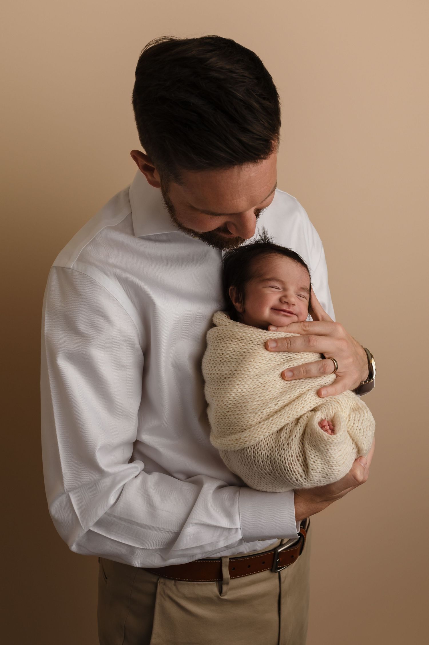 Charlottesville photographer, dad hugging smiling newborn baby daughter during studio newborn session in Charlottesville, Virginia.