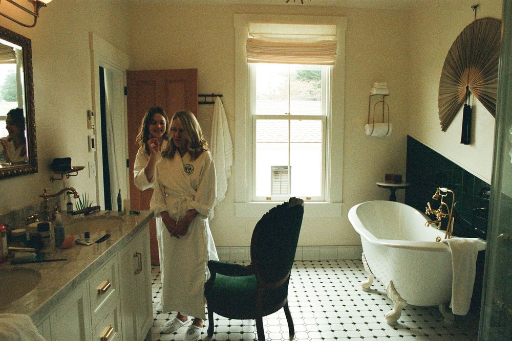 A bright bathroom interior with clawfoot tub and checkered floor tiles during wedding preparations.
