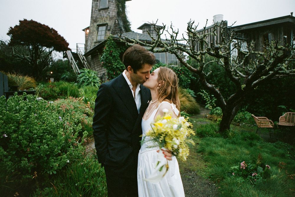 A romantic moment captured in a garden with antique architecture and twisted tree branches.