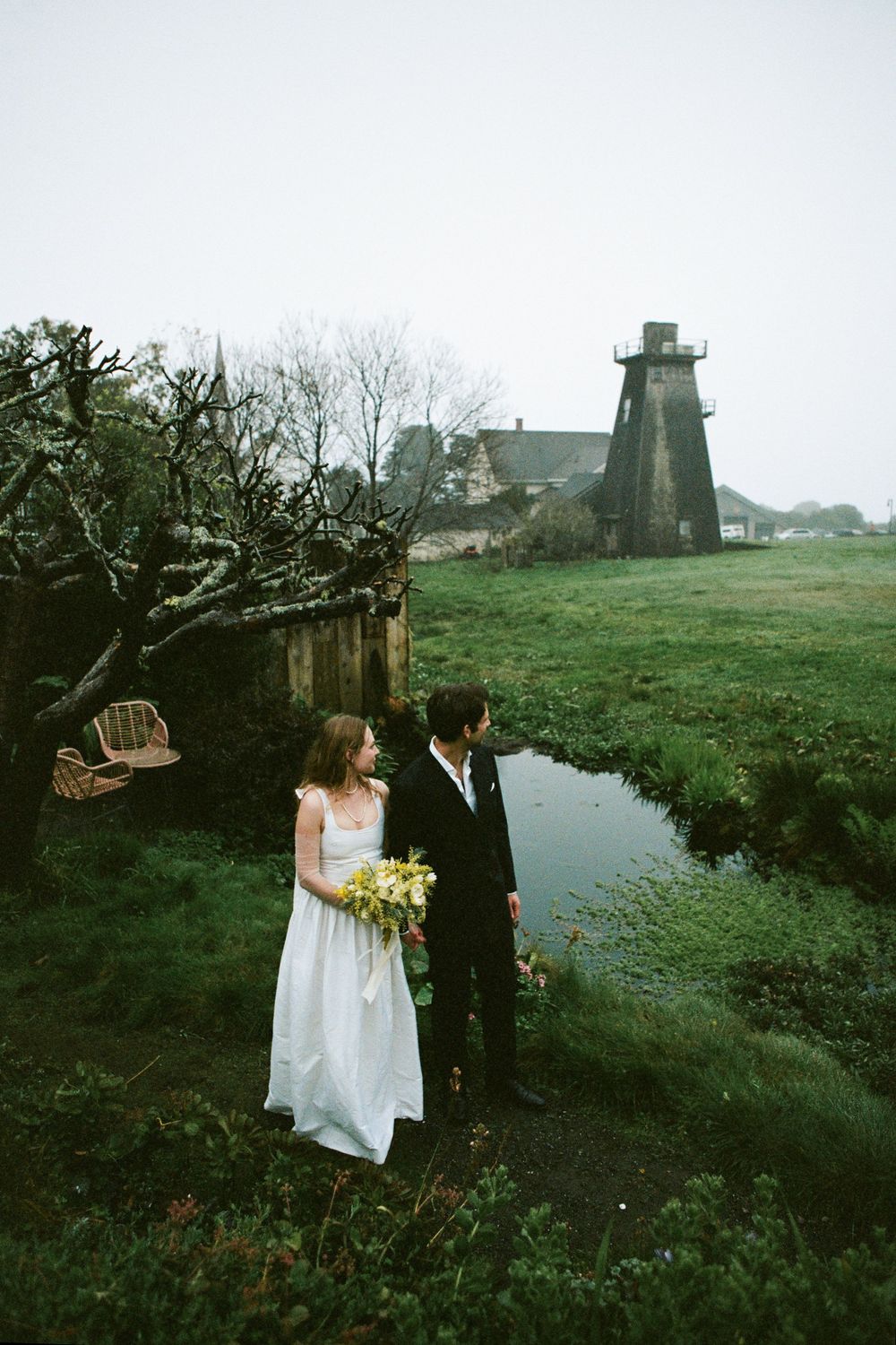 Romantic wedding portraits taken near a historic windmill and pond.