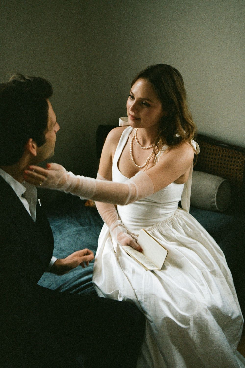 An intimate moment between a couple on a couch, with the bride wearing a classic white gown.