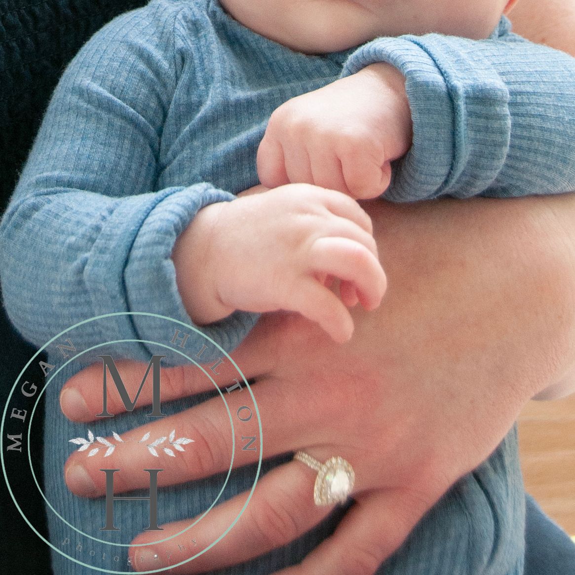 Tiny baby hands resting on mama's arm in a cozy blue sweater.