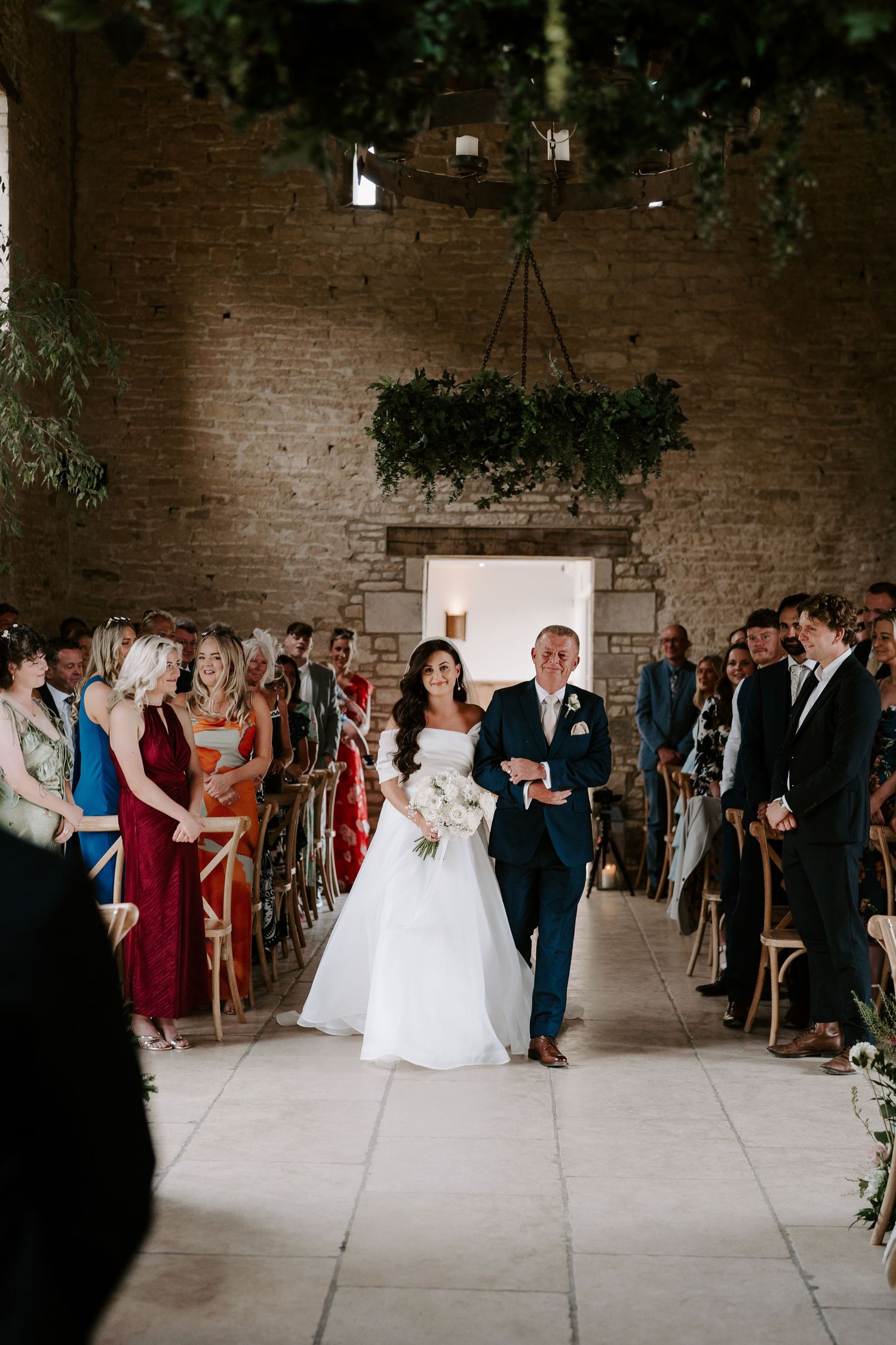 bride and dad walking down aisle during wedding ceremony at yardspace old gore in cirencester
