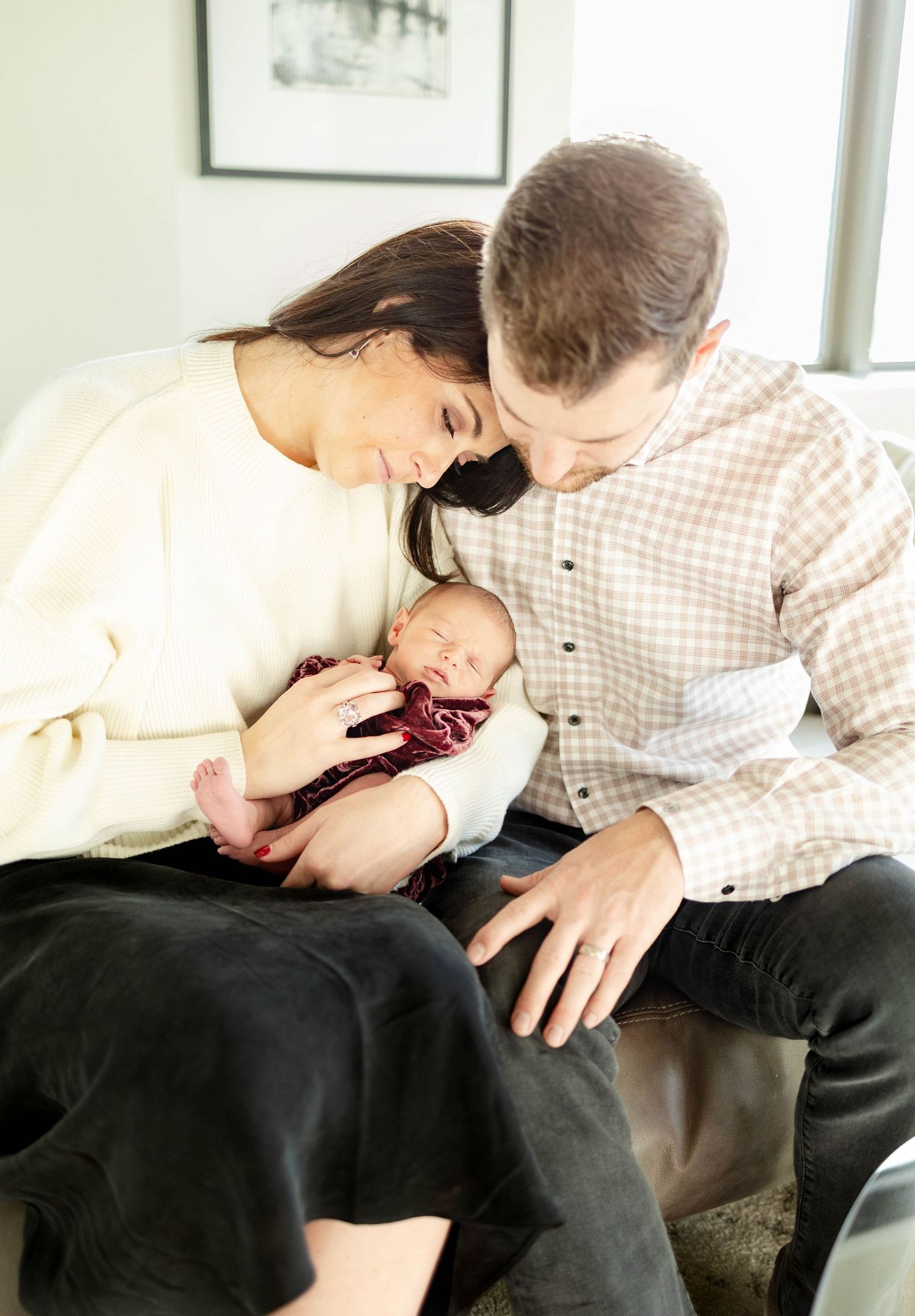 A tender family moment with a newborn baby being held and admired in a naturally lit room.