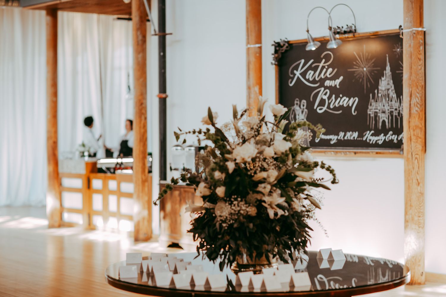 Wedding reception decor with elegant floral arrangement and chalkboard signage.