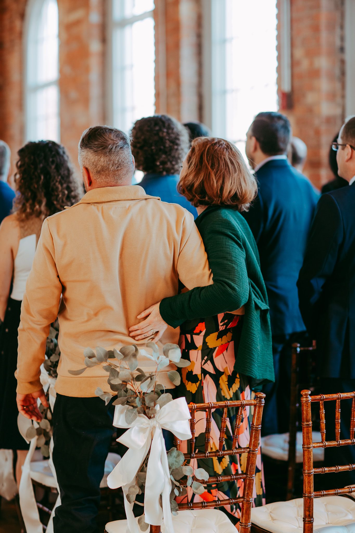 Wedding guests standing in an elegant venue with exposed brick walls.
