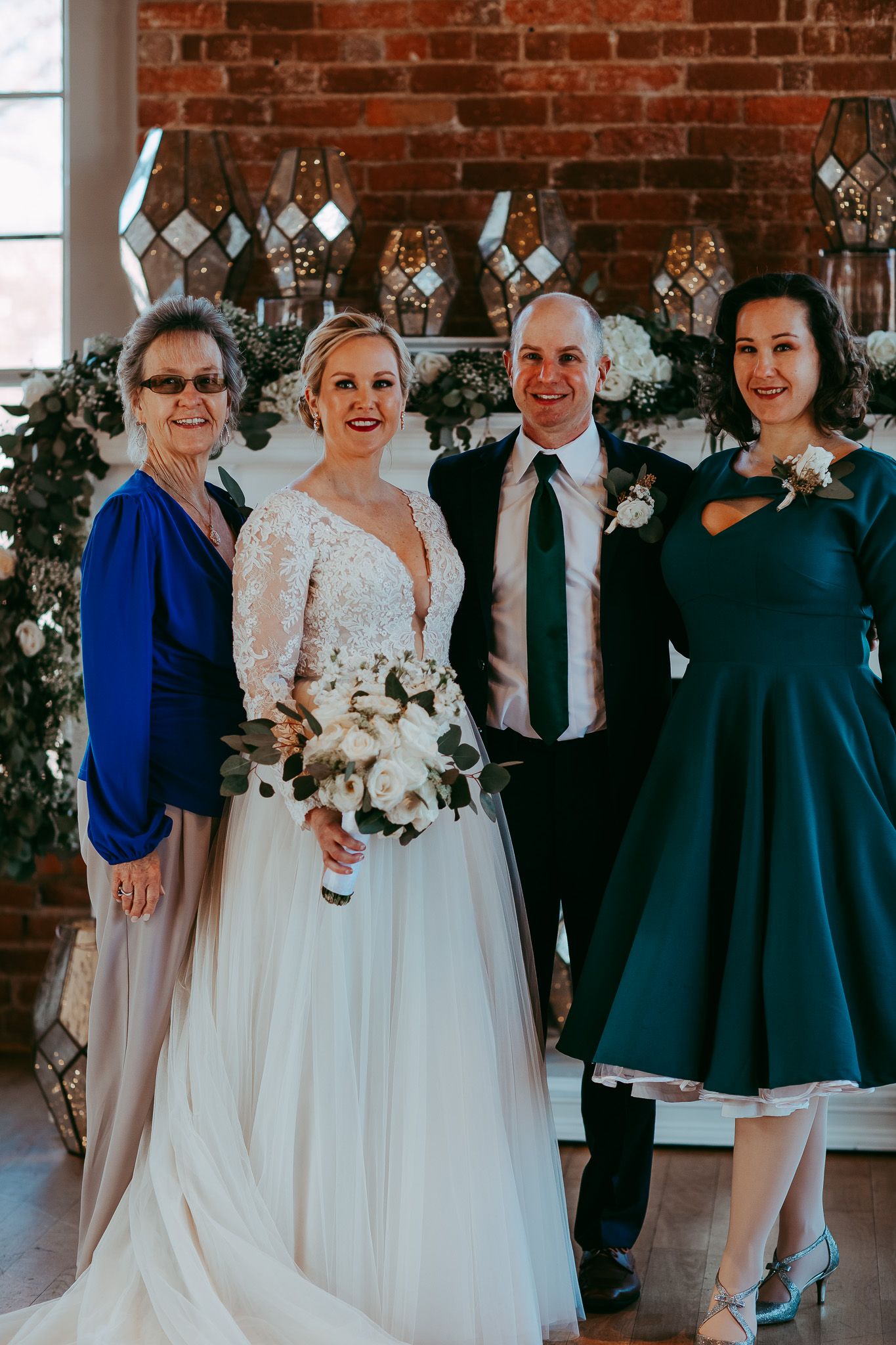 Wedding party group photo in front of brick wall with geometric decor.