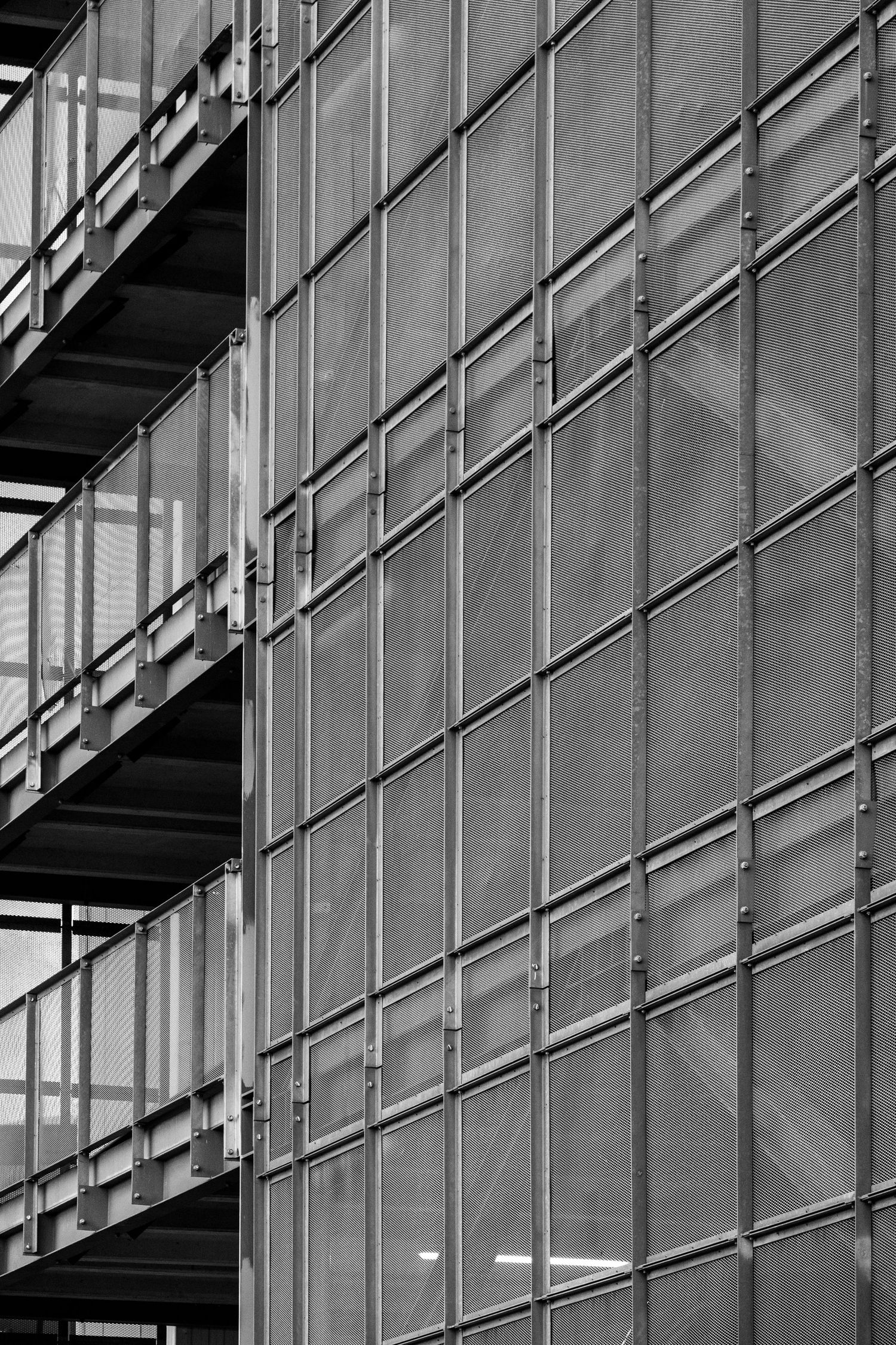 A black-and-white mesh facade wraps around a modern building in a geometric grid pattern.