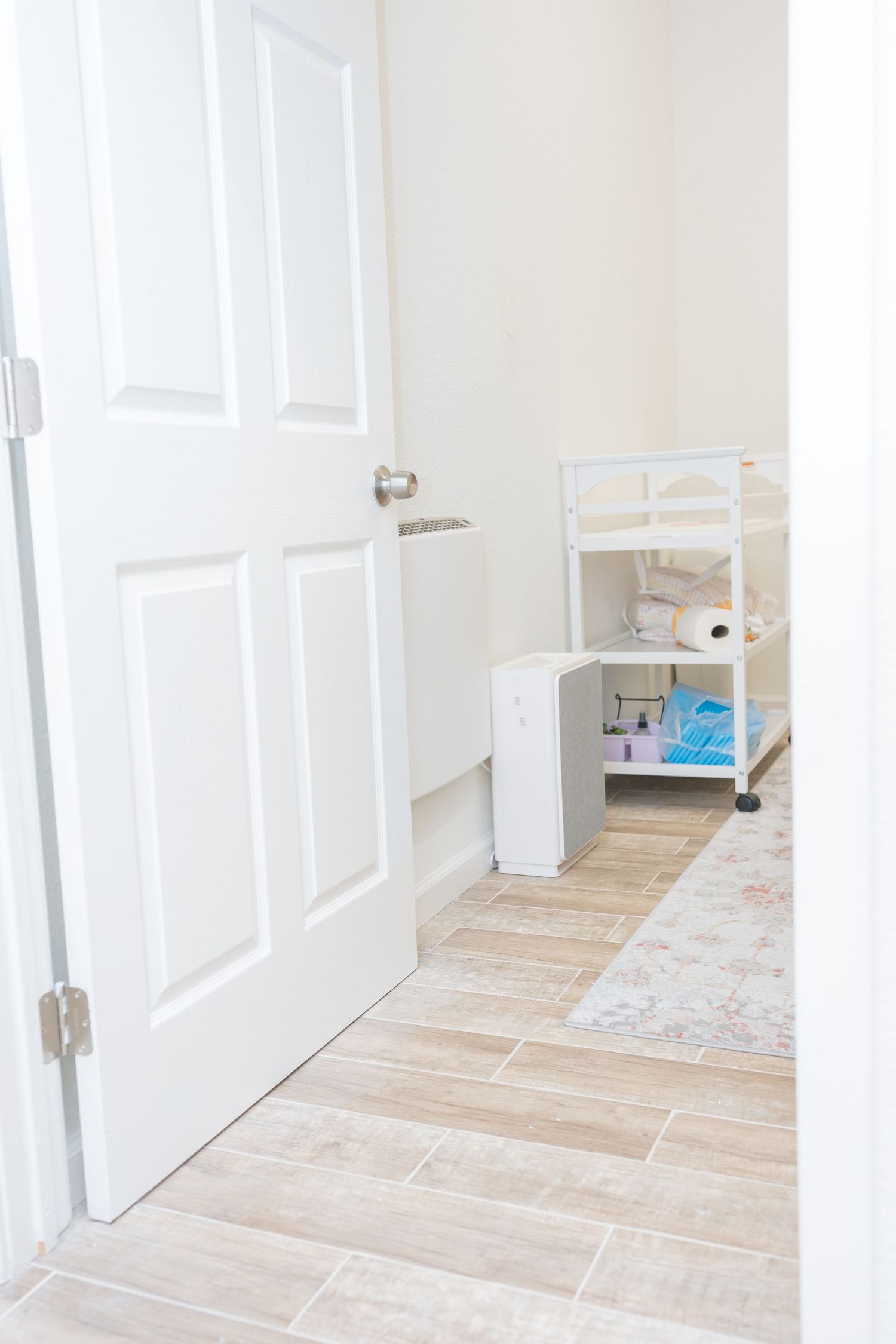 Clean white interior doorway with light wood flooring and small utility cart visible.