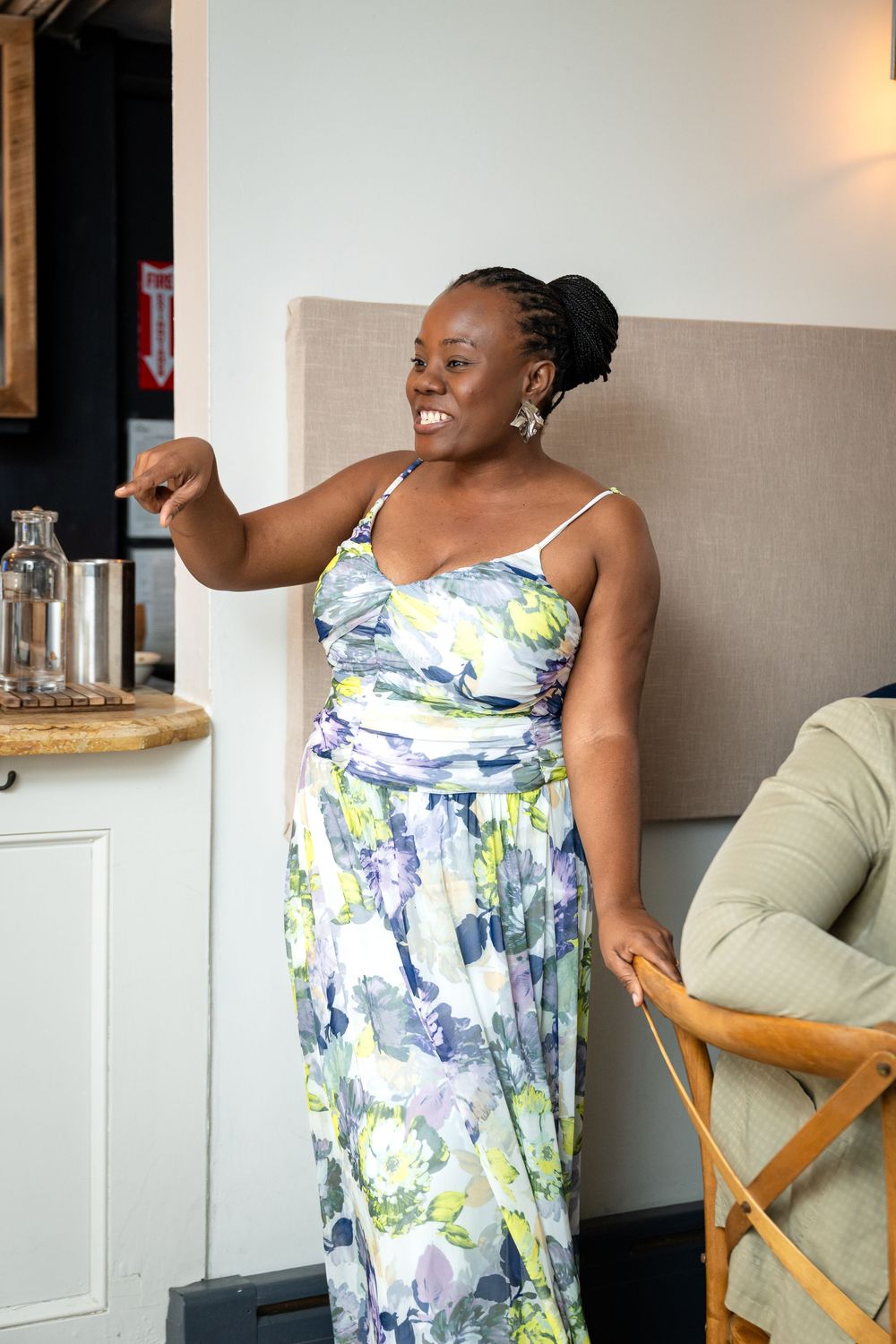 A person in a floral print summer dress gesturing expressively during a celebration.