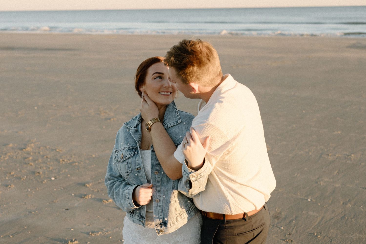 A tender moment shared between a couple on the beach during golden hour.
