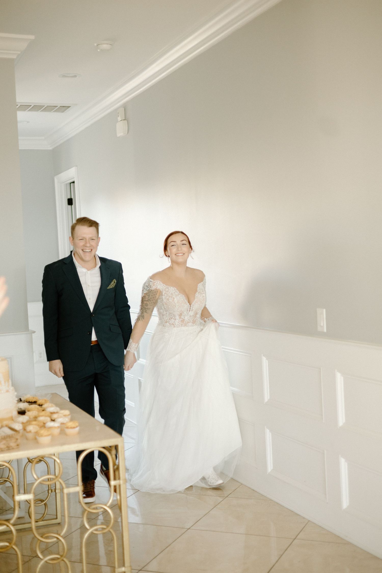 Elegant film-style wedding photos showing a couple in black suit and white gown walking through a bright modern venue.