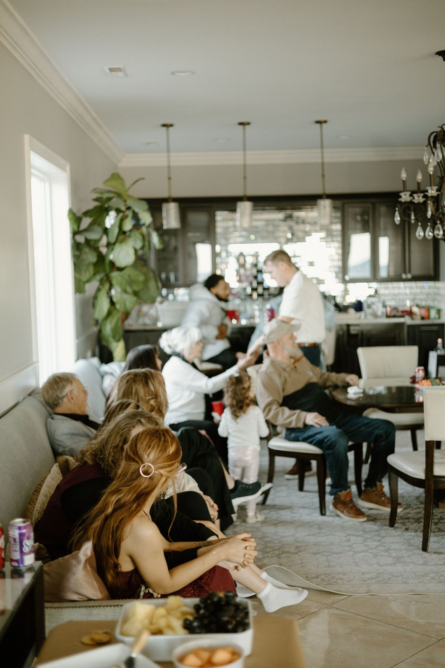 Diners enjoy a casual meal in an upscale restaurant with pendant lights and a large houseplant by the window.