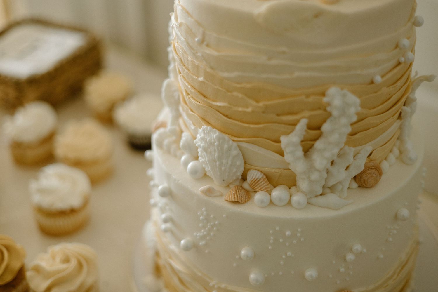 Close-up detail of an elegant white wedding cake decorated with delicate pearls and ruffled fondant details.
