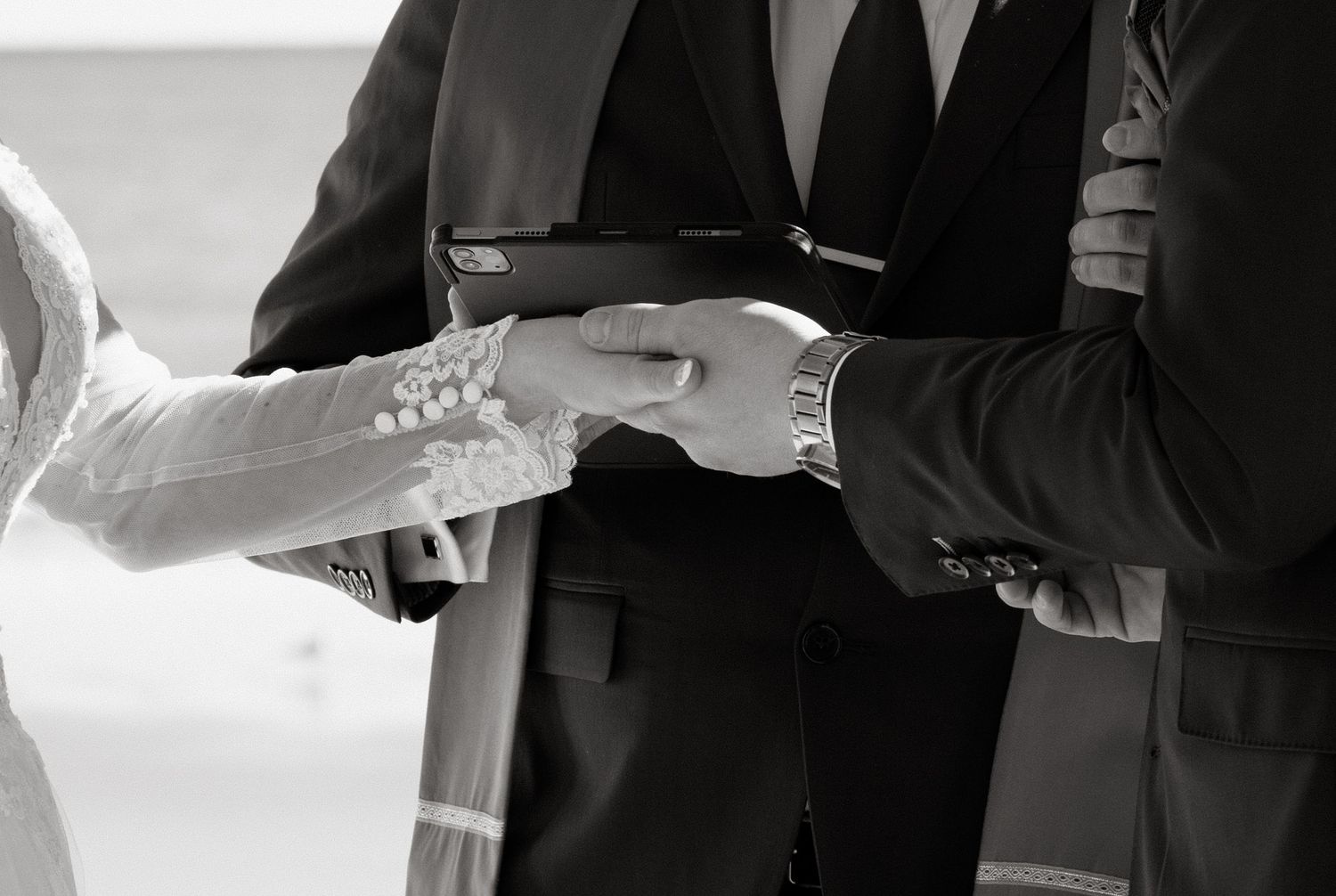 Close-up black and white photo of hands during a traditional ring exchange ceremony at a wedding.