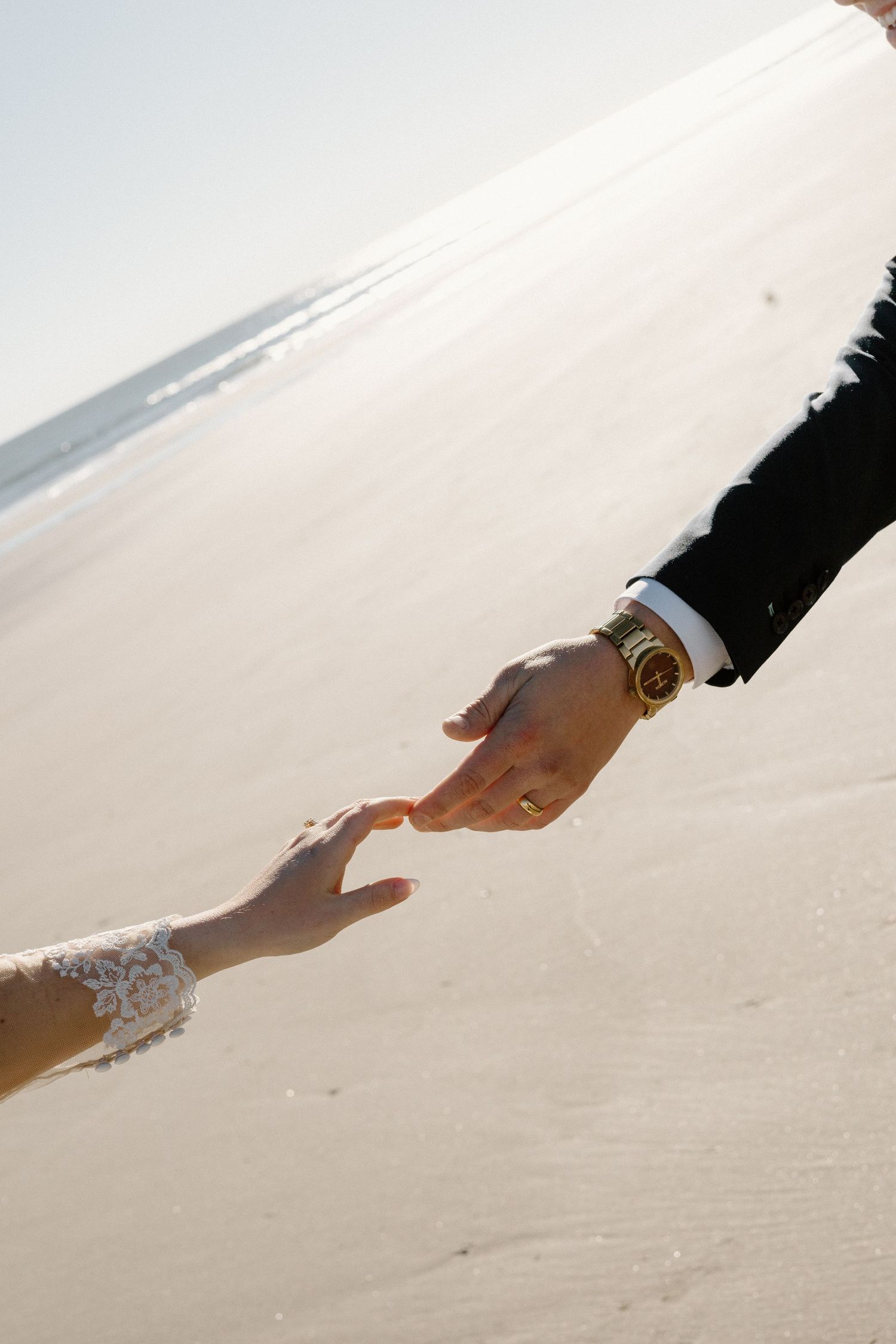Hand reaches down to write in pristine white sand on a sunny beach creating a message or drawing.
