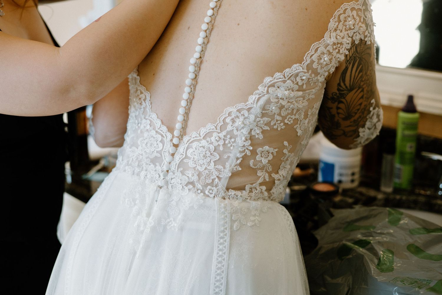 Close-up detail of a white lace wedding dress bodice with delicate button closures down the back.