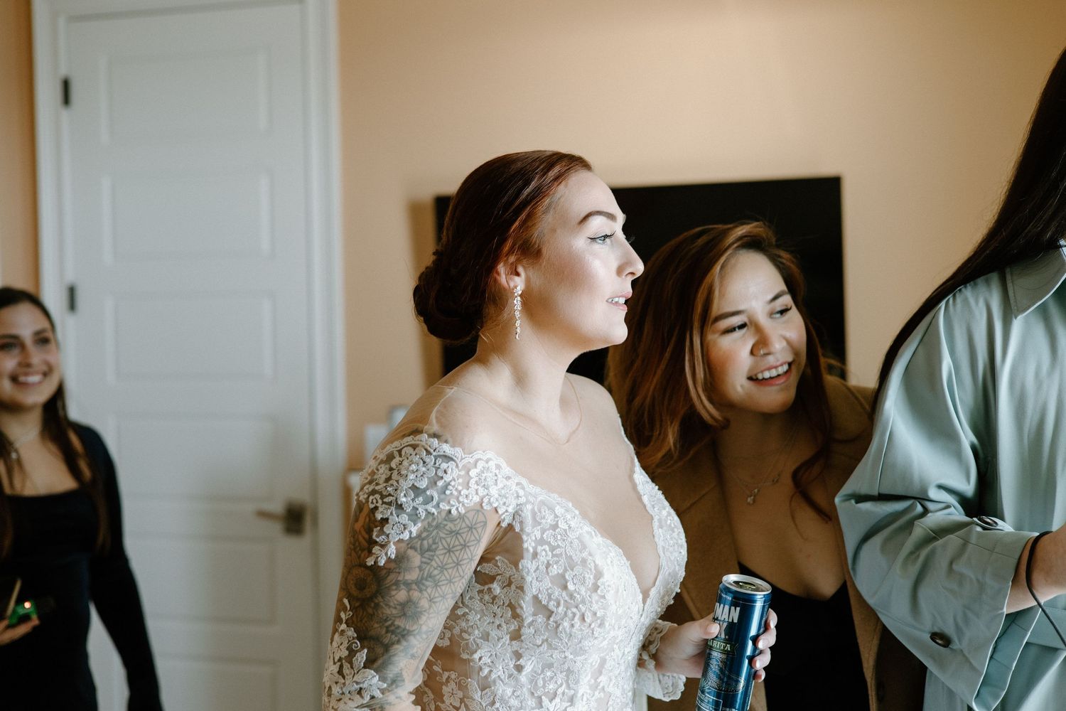 A bride getting ready in white room surrounded by bouquet of white wedding flowers.