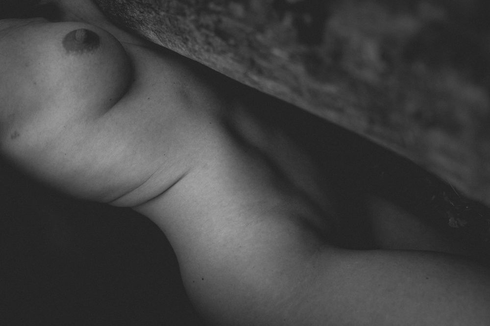 Abstract black and white artistic nude photography study showing curves and shadows.
