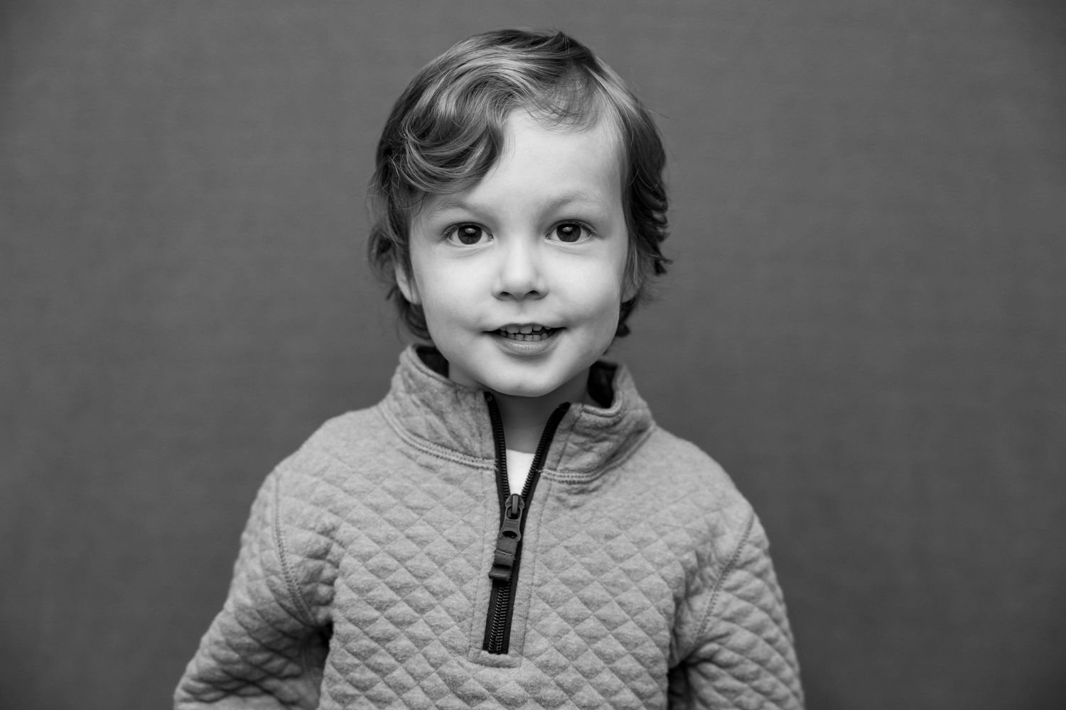 A series of black and white headshots showing the same child at different angles wearing a quilted jacket.