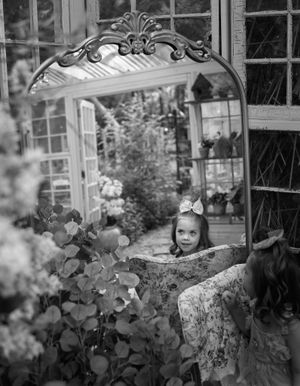 Artistic black and white portraits framed by garden foliage and window panes.