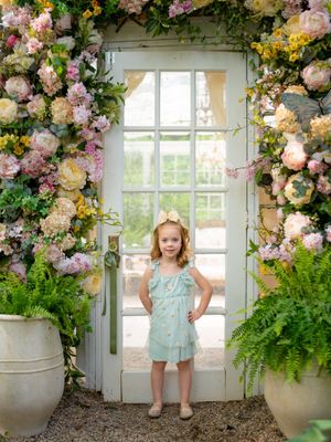 Beautiful garden setting with floral archway, potted plants, and mint green outfit details.