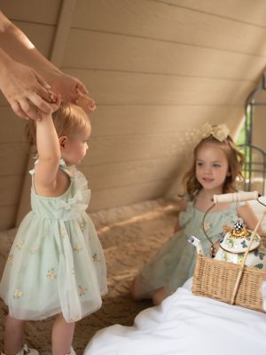 Light mint dress against beige background with wicker basket and delicate details.