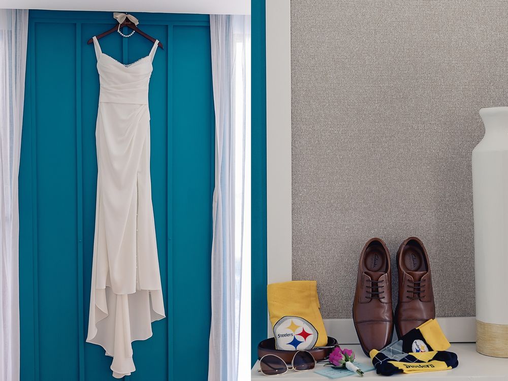 A white wedding dress hangs on a turquoise wall next to brown dress shoes and sports memorabilia on the floor.