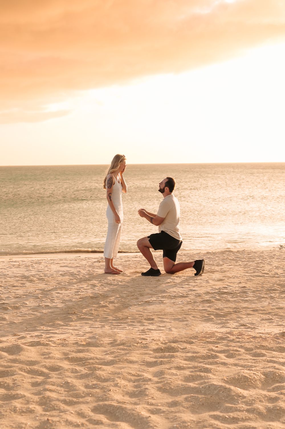 Partner getting down on one knee during a beach proposal photography ses