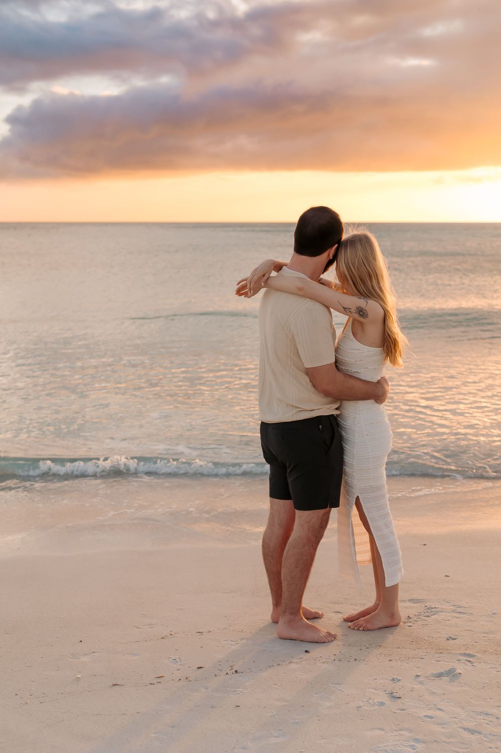 Newly engaged couple celebrating on the shoreline at golden hour