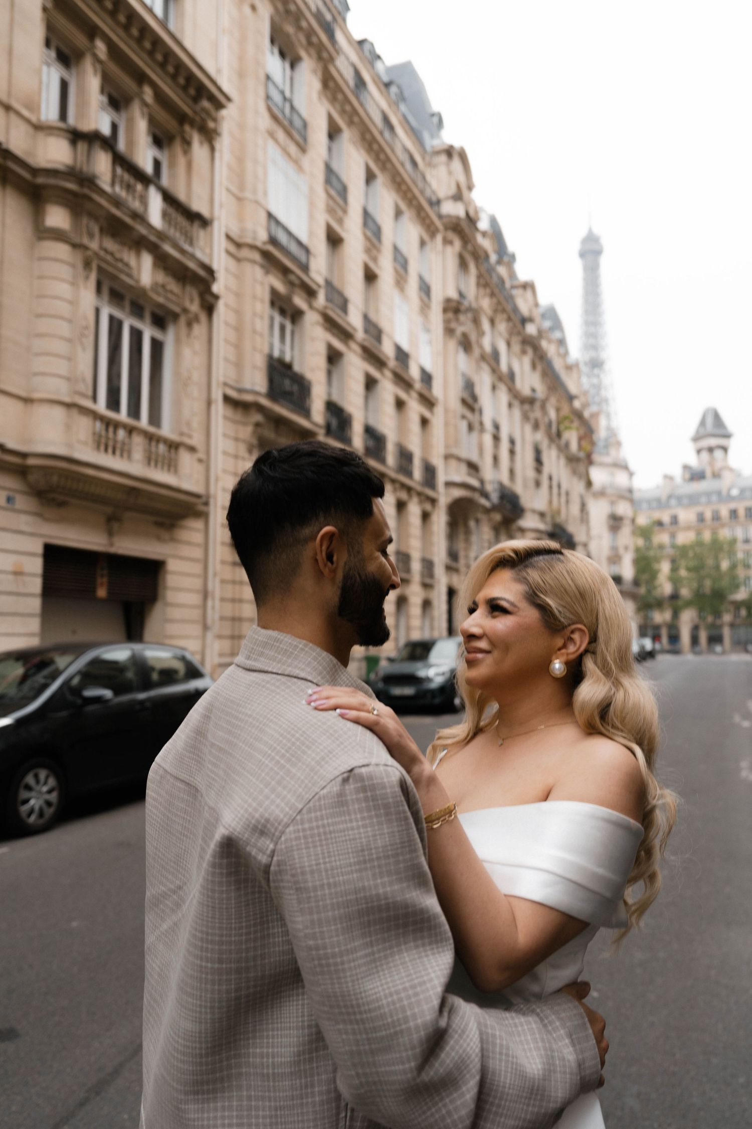 Romantic couple embraces on a Parisian street with the iconic Eiffel Tower visible in the distance.