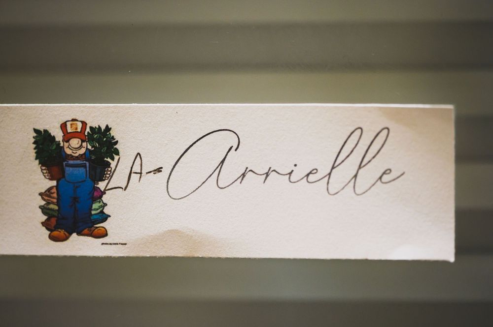 A white wooden name tag or sign featuring a cartoon mascot and handwritten signature.