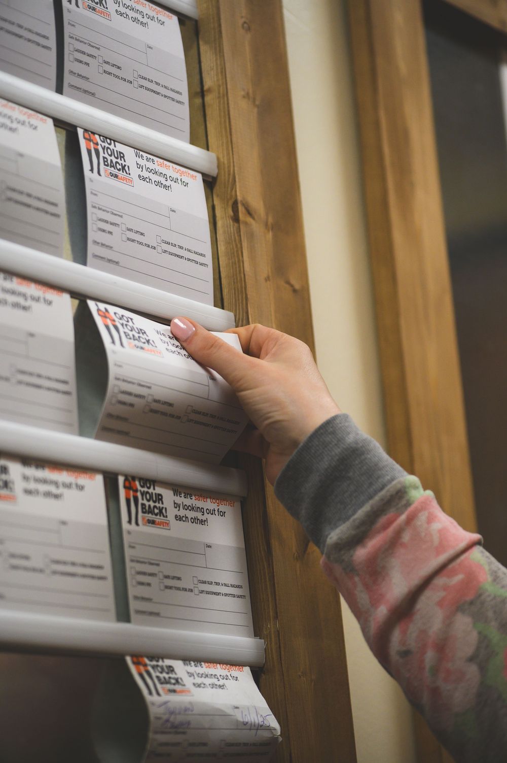 Hand reaching for paperwork on a wooden shelving unit filled with organized documents.