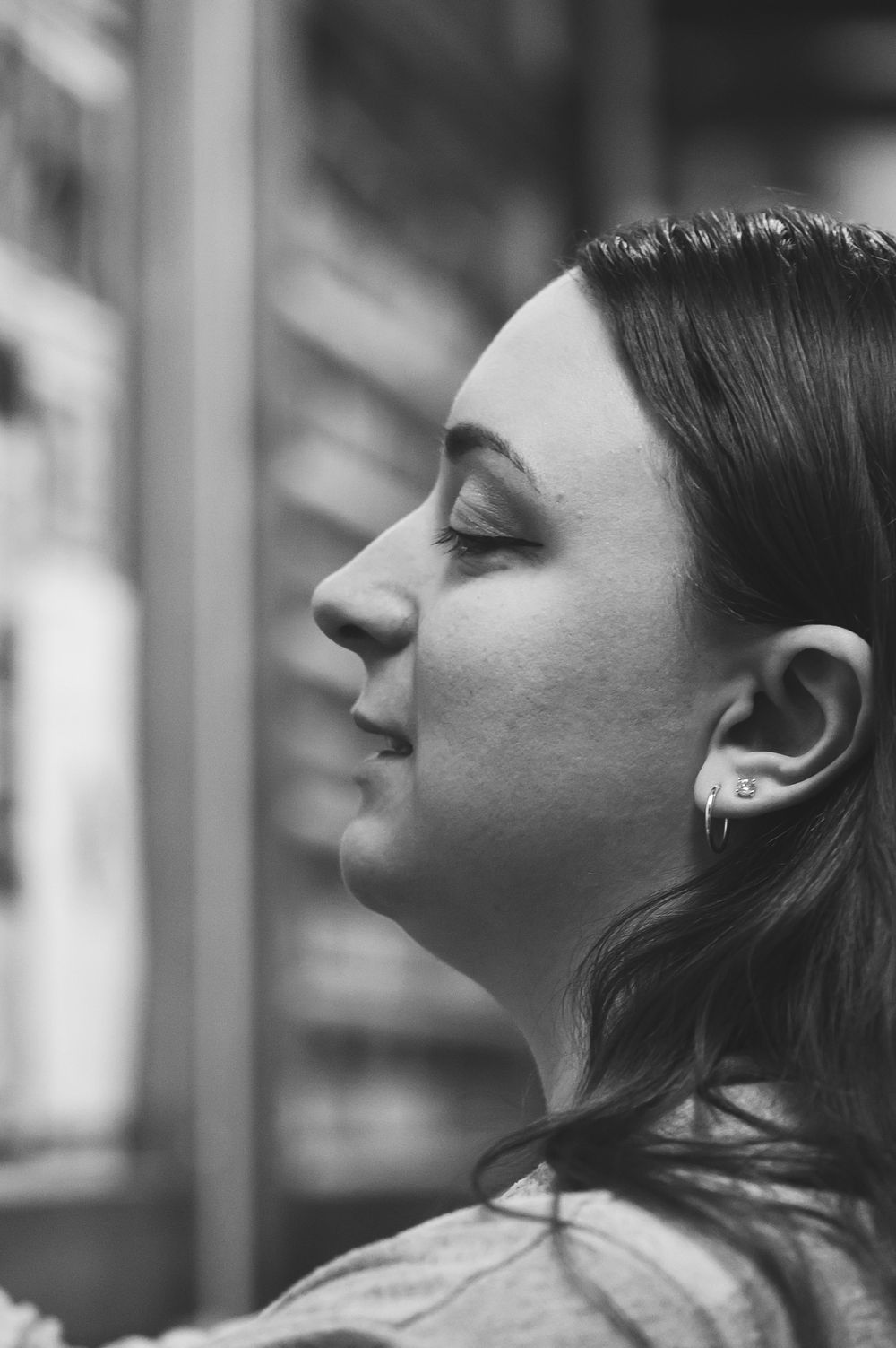 Black and white profile portrait of someone with dark hair and earrings in a serene pose with eyes closed.
