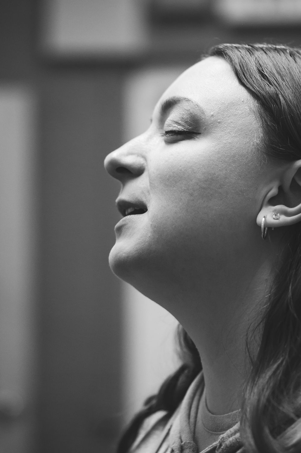 Black and white profile portrait showing emotion with eyes closed and earrings visible.