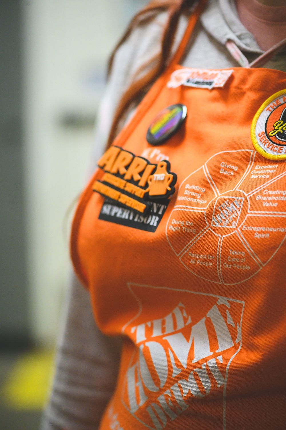 Close-up details of white diagrams and text on an orange Home Depot workplace safety apron.