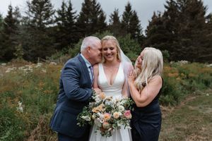 Joyful wedding couple shares intimate moments surrounded by evergreen trees during outdoor mountain photo session.
