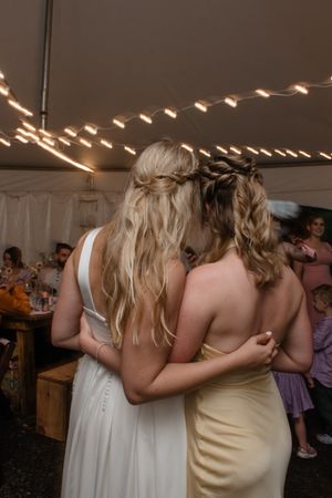 Groups of wedding guests share emotional embraces and dance together at a reception celebration.