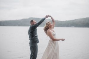 Two people dancing playfully by a misty lake with mountains in the background as one spins the other.
