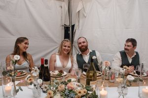 Wedding reception dinner table with guests enjoying a candlelit meal and wine.