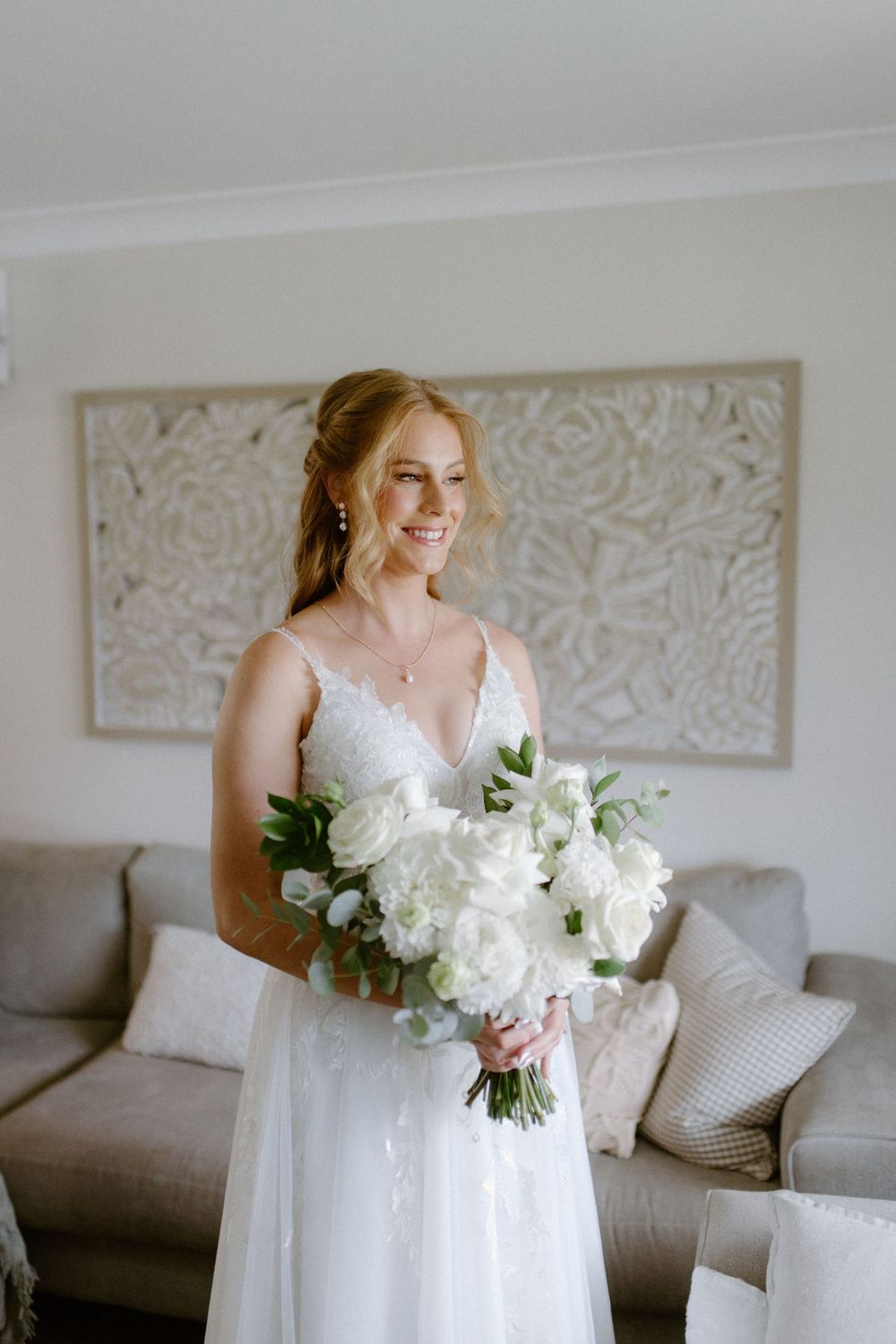 A wedding preparation scene with a white bridal gown and bouquet of white flowers.