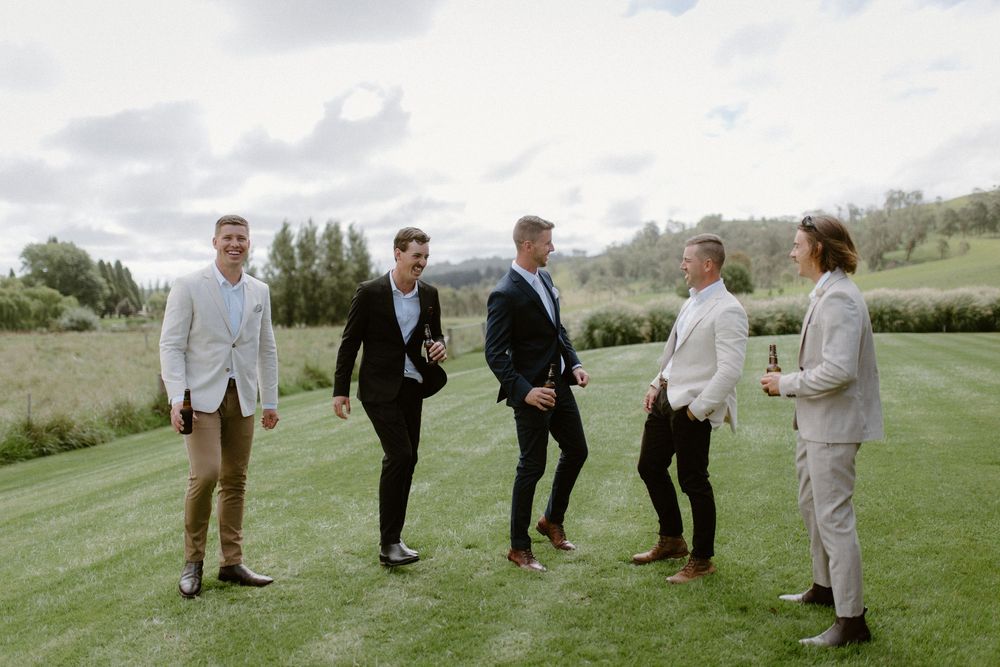 Wedding party members walking and chatting on a lush green lawn.
