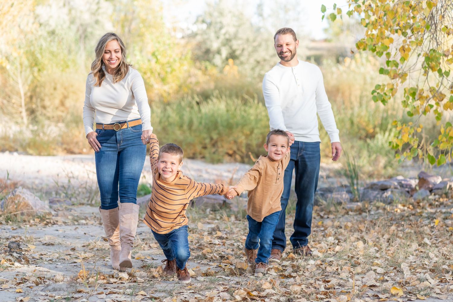 Family walking together and holding hands on an autumn path through nature with fall foliage in the background.