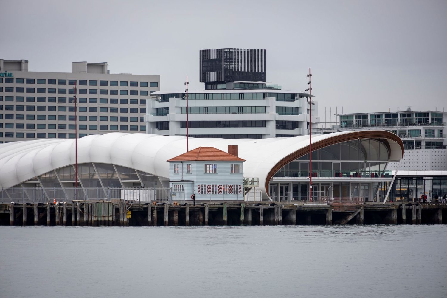 White arched terminal buildings line the pier with a central heritage house in contrast.