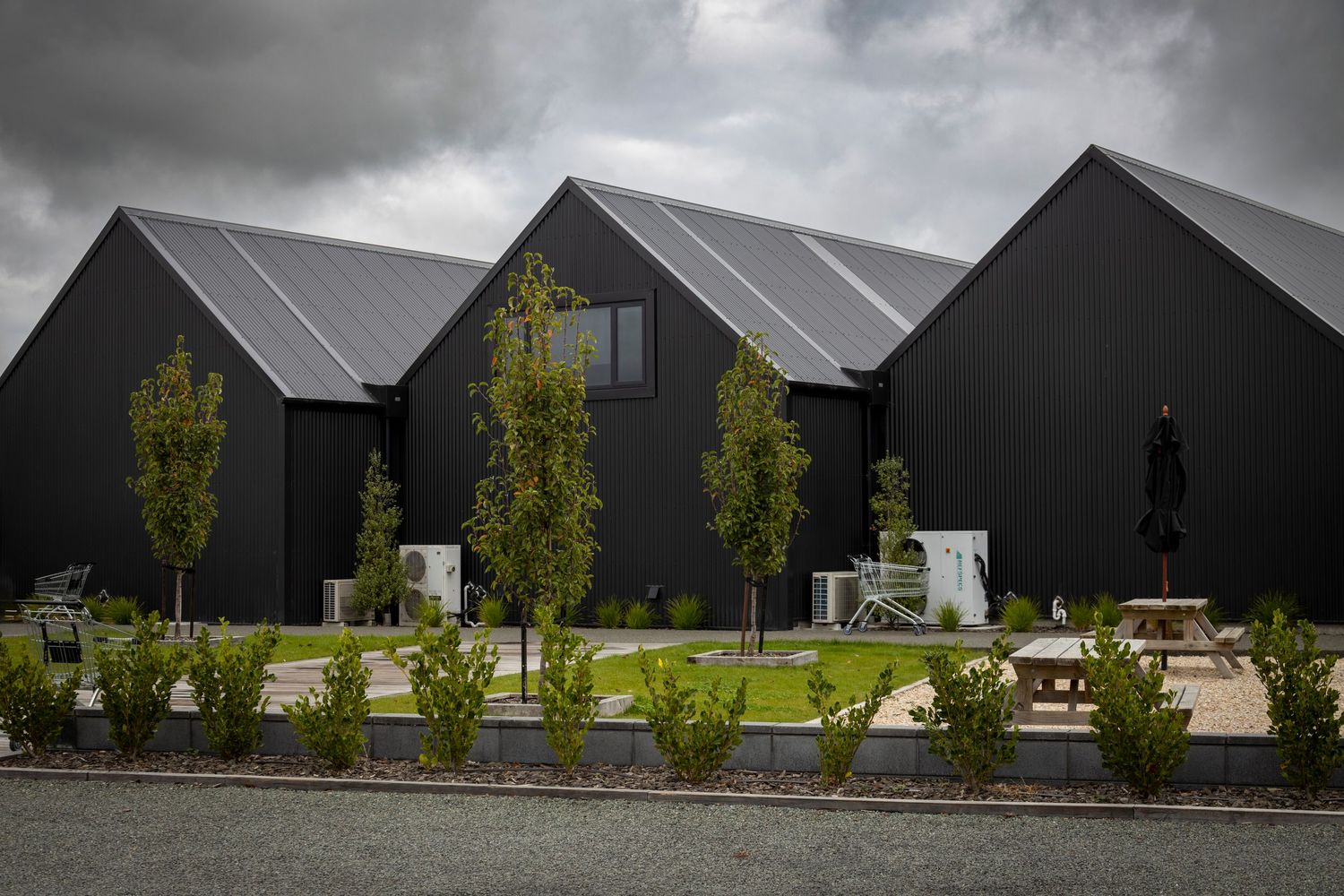 Sleek black steel gable buildings surrounded by minimal landscaping.