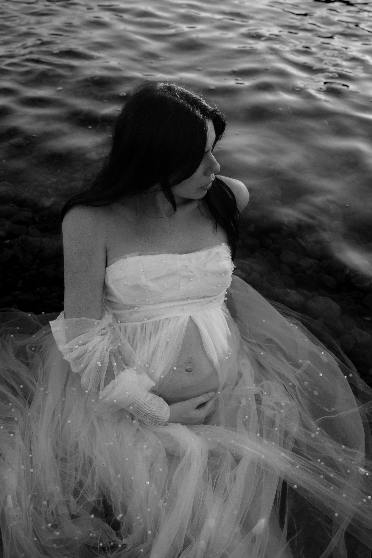 intimate maternity portrait of an expecting mom on the rocks at the wild beach of tenerife