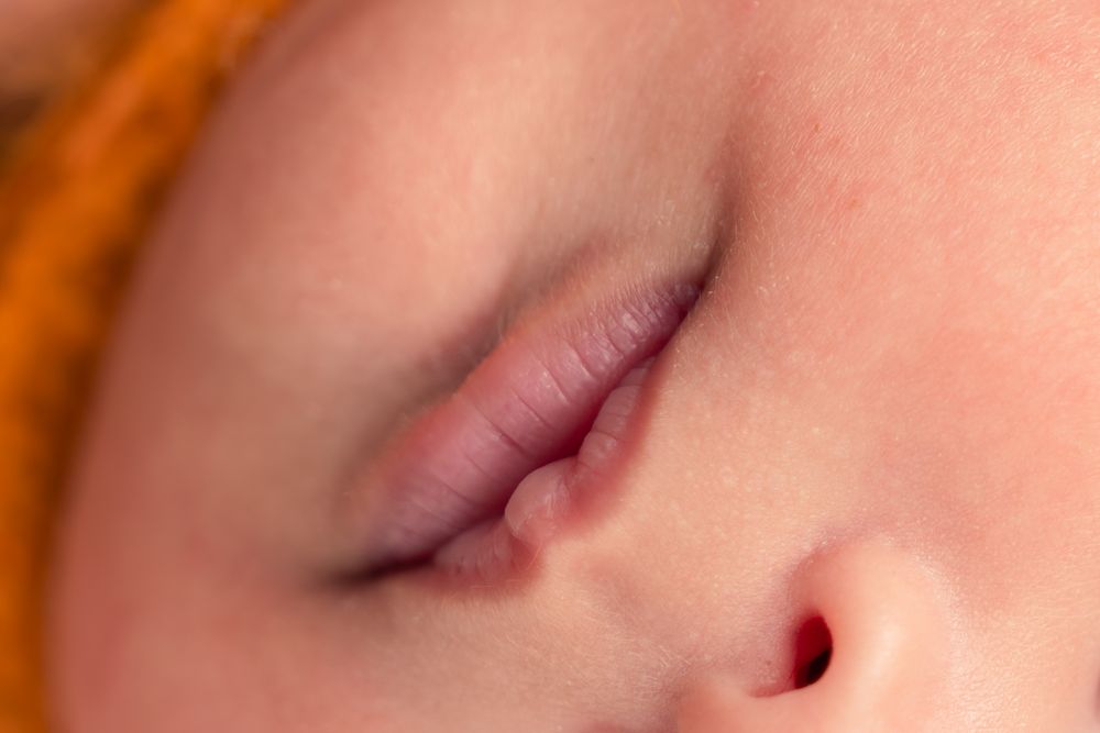 Close-up of a sleeping newborn baby's lips and nose with soft skin texture.