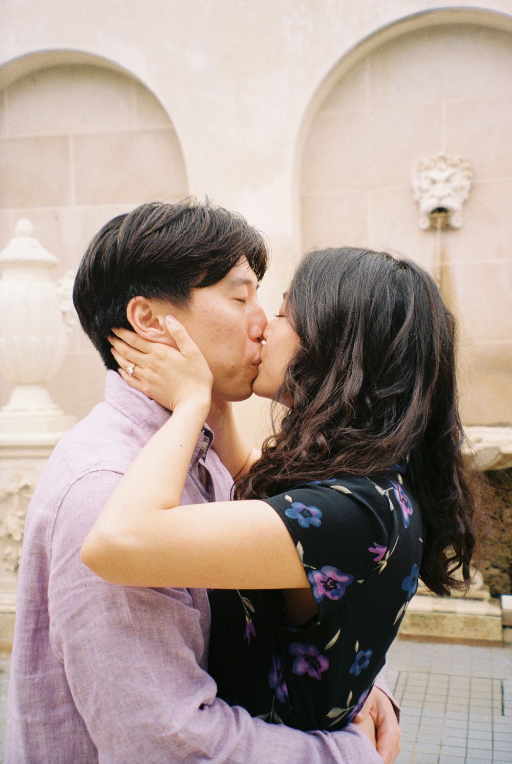 Couple sharing a tender moment against a white arched backdrop.