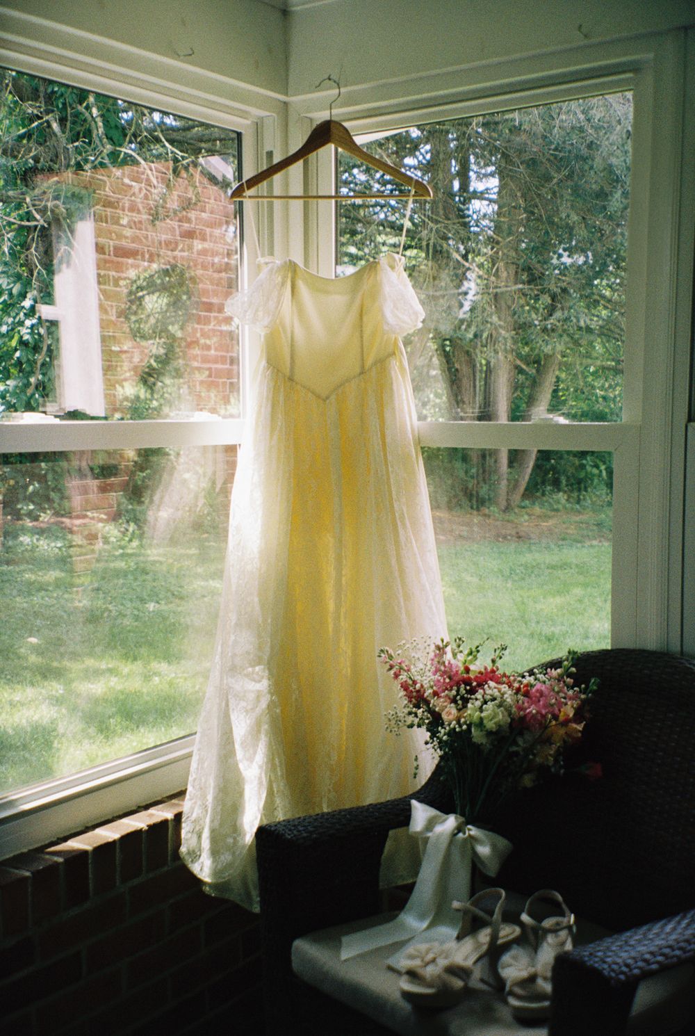 A yellow dress hanging in a sunlit window with natural light streaming through.