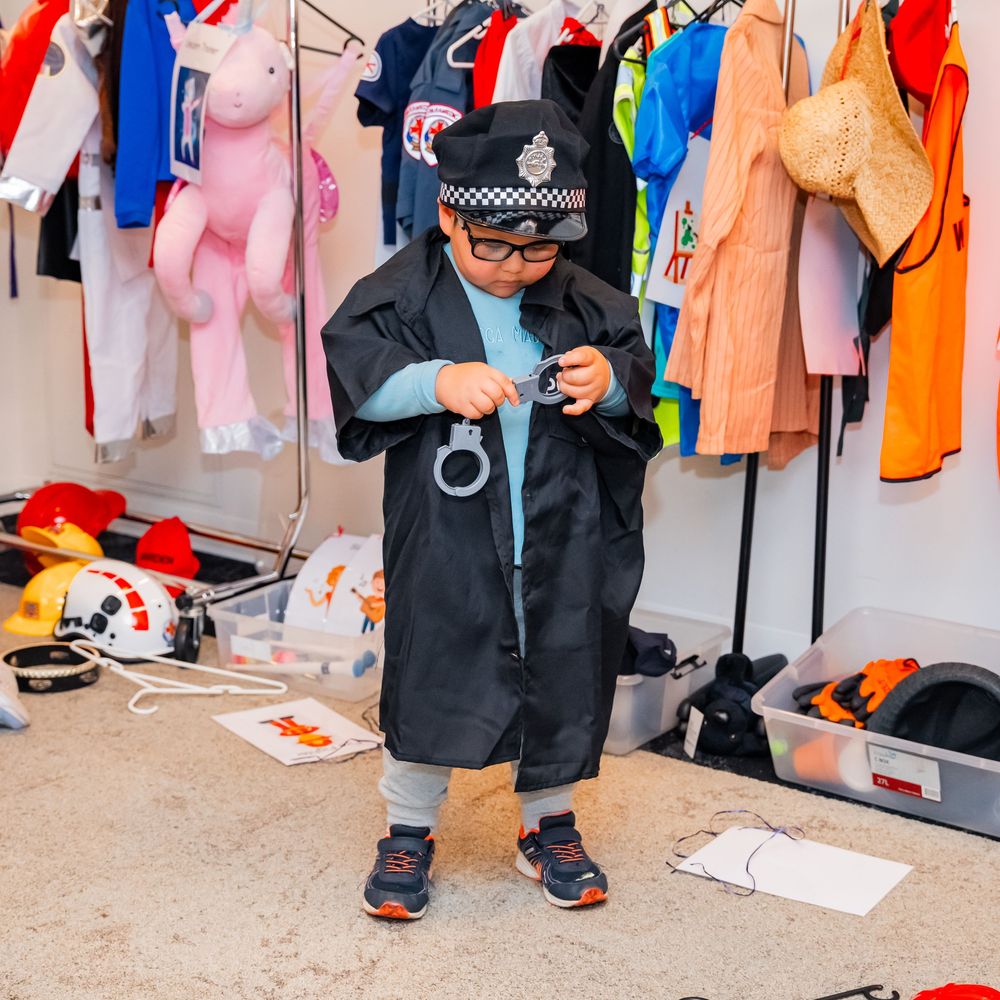Colorful costumes and clothing items hanging on garment racks backstage at a theater or performance venue.